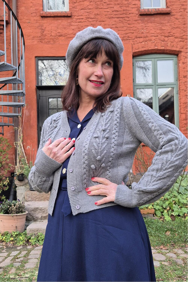 Grå langermet merinoull cardigan med kabelstrikk og knapper – fra Manillusion, Oslo.