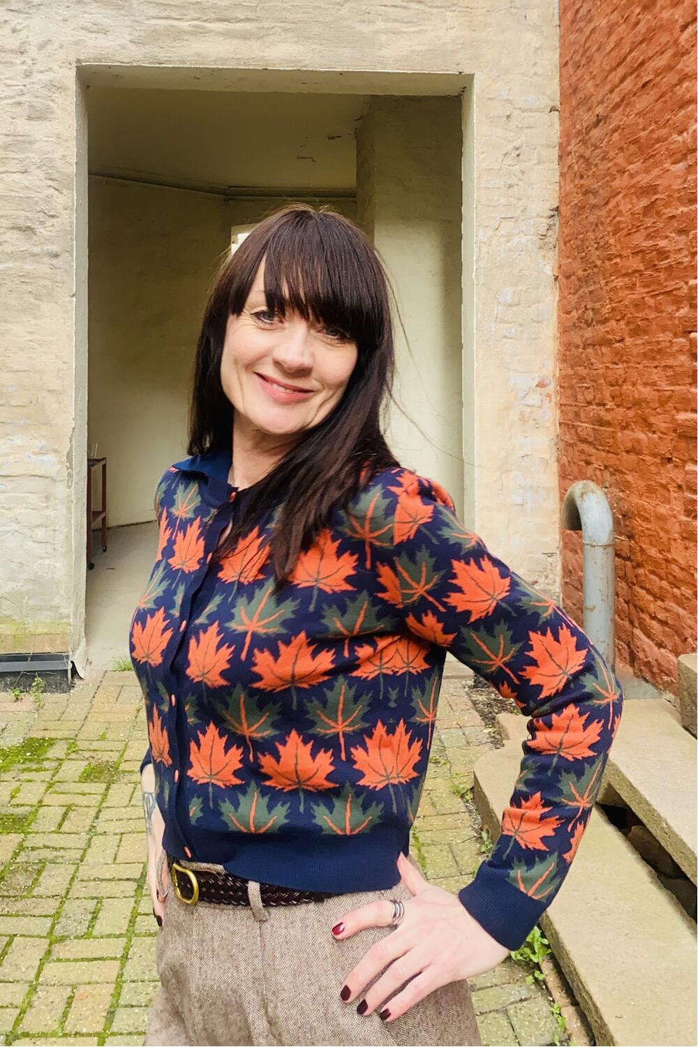 Blå cardigan i økologisk bomull med oransje og grønne høstblader – fra Manillusion, Oslo.